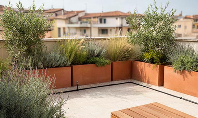 Terrazzo urbano nelle Marche con fioriere mediterranee, sedute in legno e irrigazione a goccia